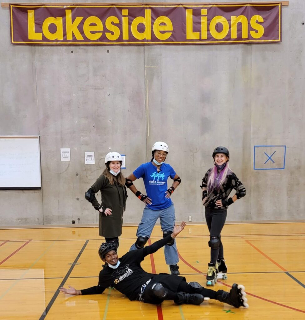 Four people in roller skates in gym.