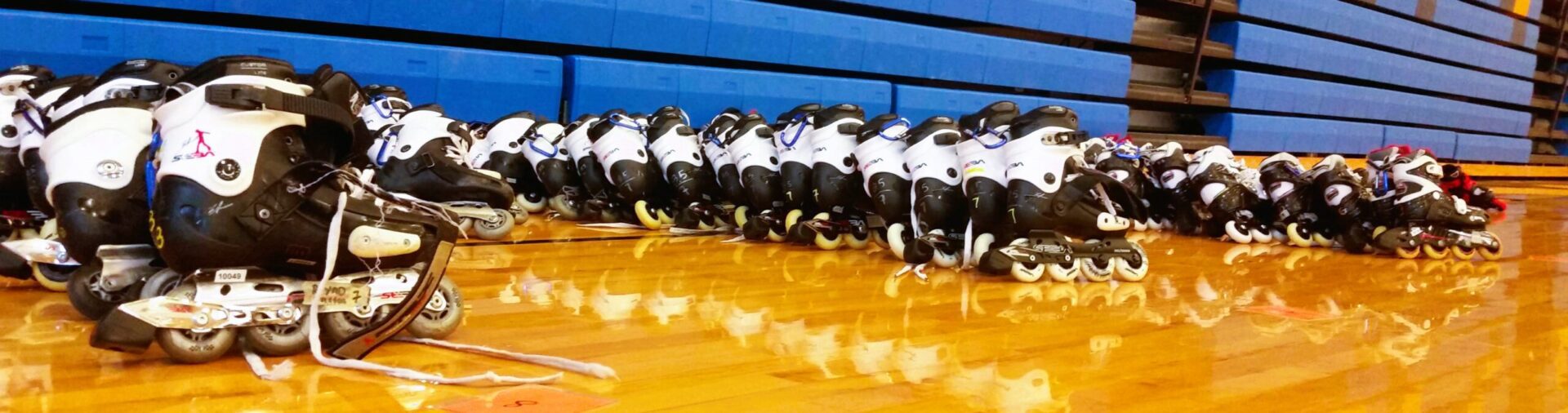 Inline skates lined up on wooden floor.