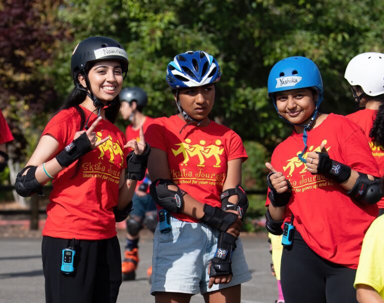 Three girls wearing helmets and red shirts.