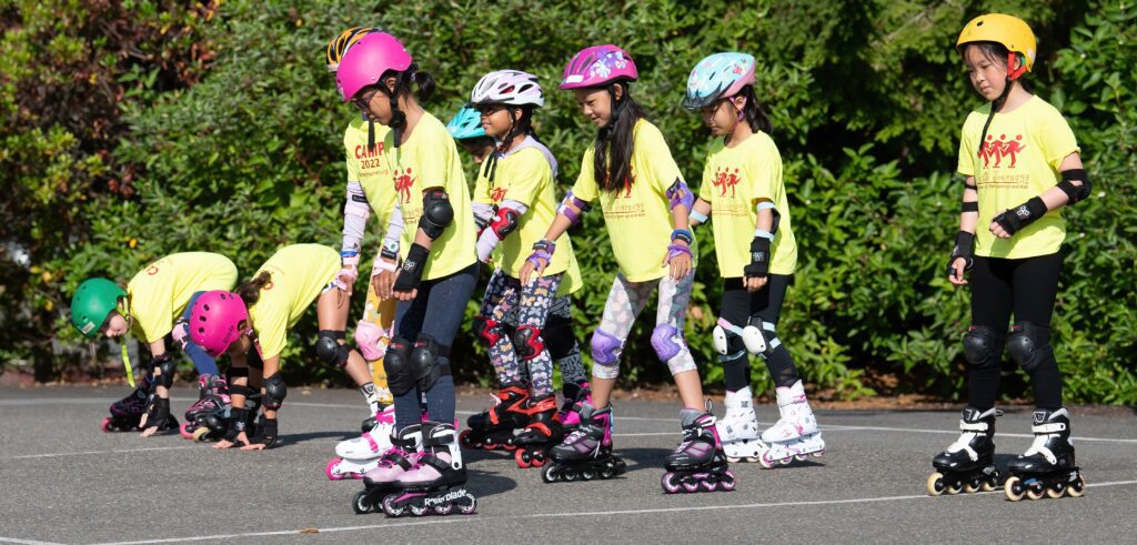 Kids in helmets rollerblading outdoors.