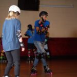 Man in blue shirt roller skating indoors.