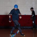 Man in helmet rollerblading past cones.