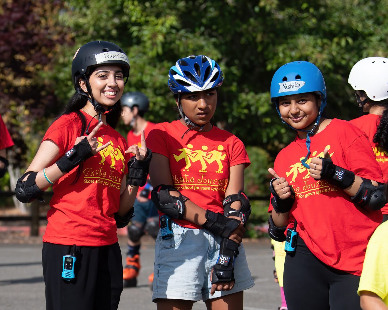 Three girls wearing helmets and red shirts.