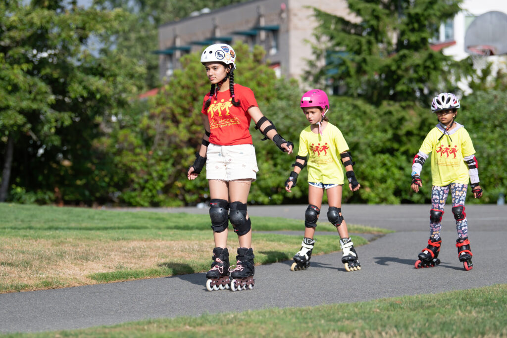 Three children rollerblading in a park.