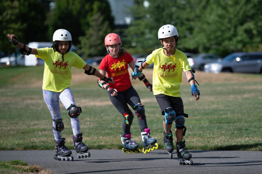 Three kids rollerblading on a path.