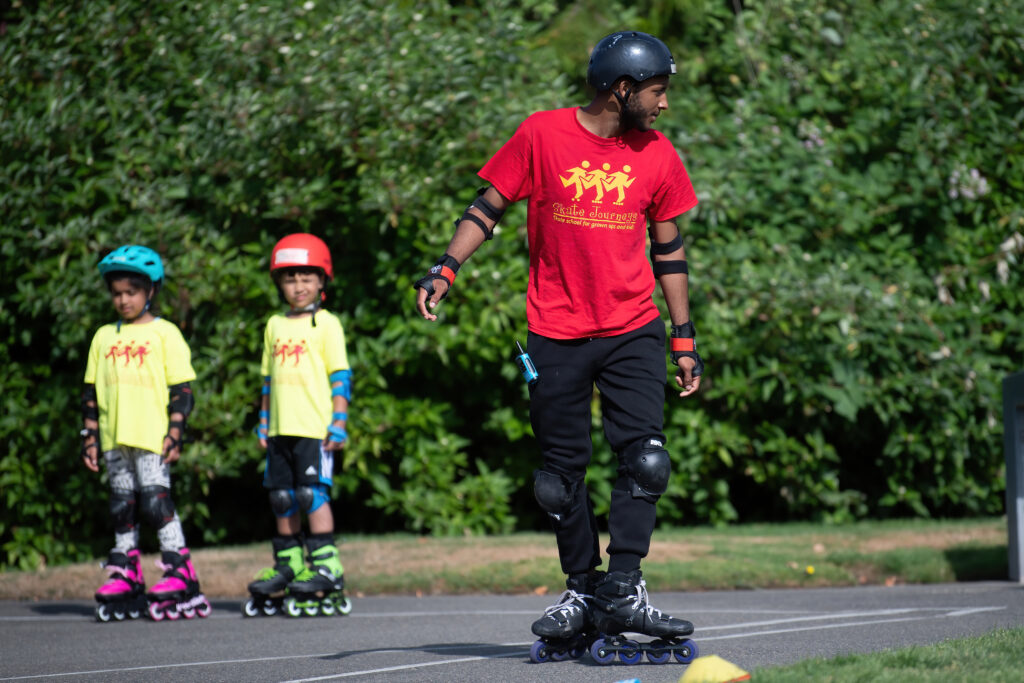 Adult and children rollerblading in a park.