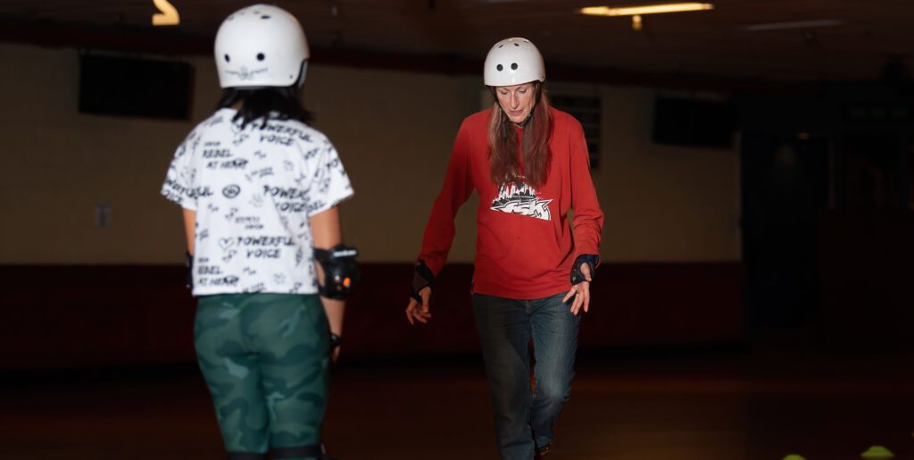 Two women roller skating at a rink.