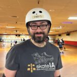 Man in roller rink wearing helmet and pads.