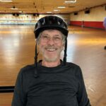 Man wearing a helmet at a roller rink.