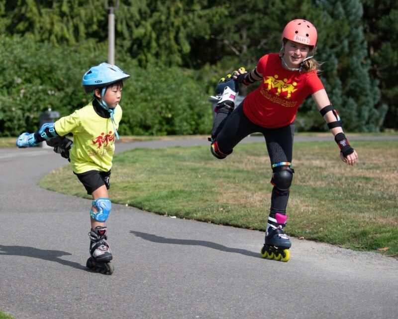 Two kids rollerblading on a path.