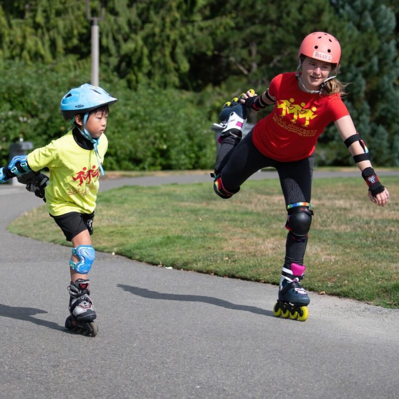 Two kids rollerblading on a path.