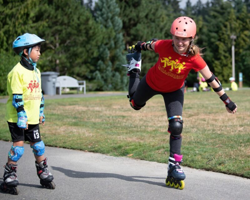 Two young people rollerblading in park.