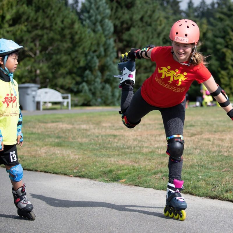 Two young people rollerblading in park.