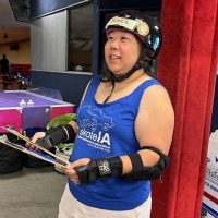 Woman in blue tank top holding roller skates.