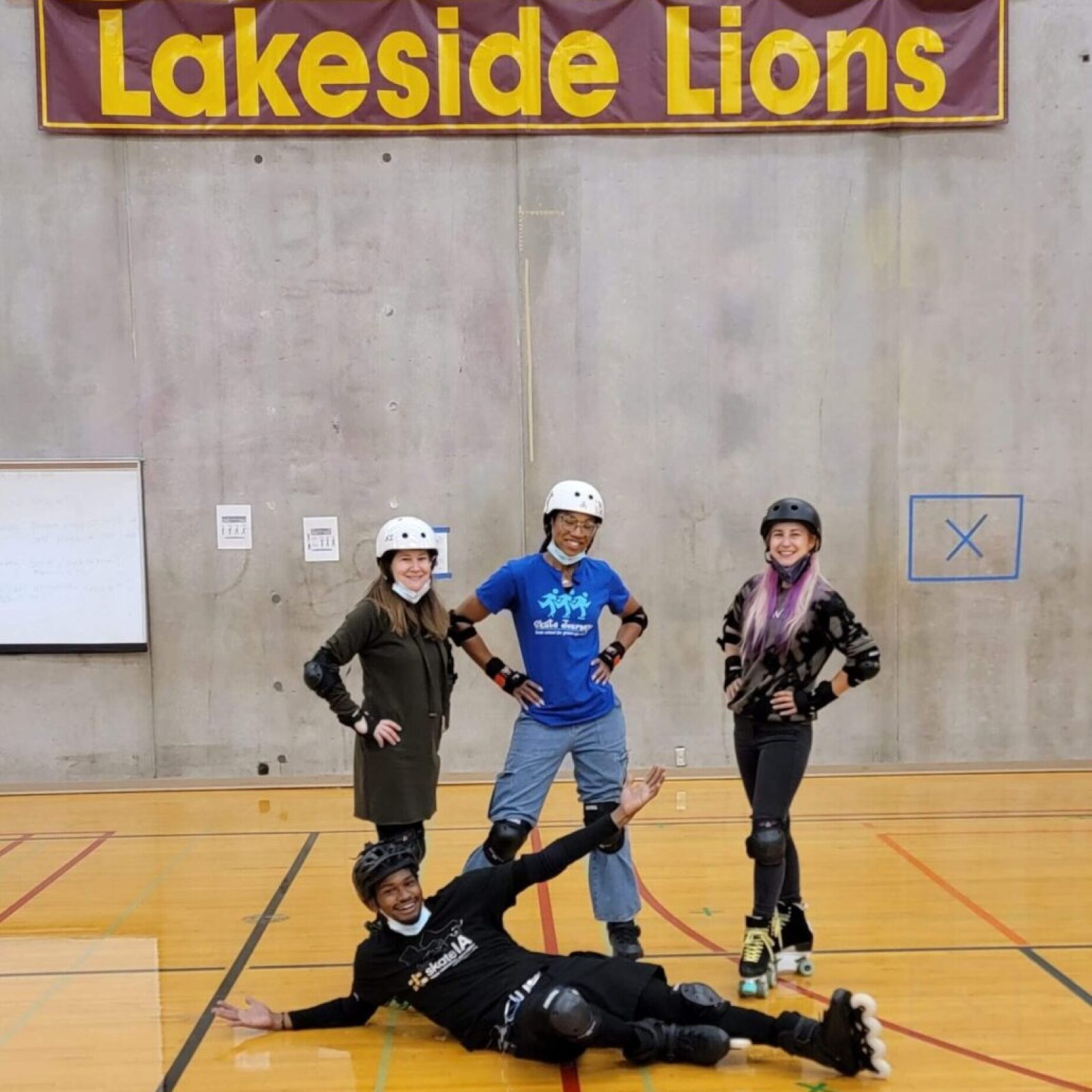 Four people in roller skates in gym.